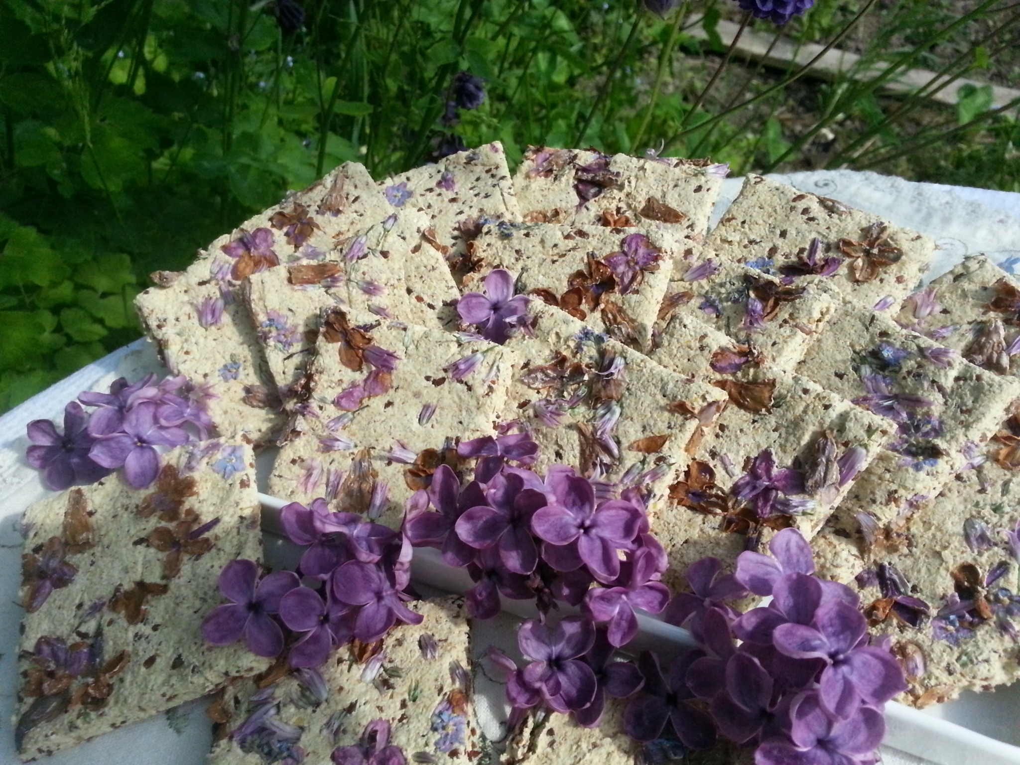 Diese roh-veganen Fliederkräcker bestehen aus einem relativ feingemahlenen Buchweizen-Leinsamenteig, in dem die farbigen Blüten sehr schön zur Geltung kommen :-) 